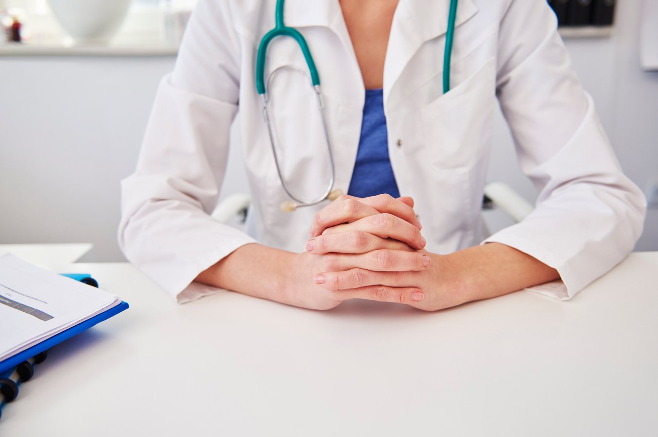 Detail of a doctor sitting behind a desk.